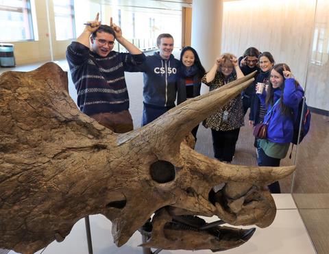 people posing for a photo by making horns on their heads with the triceratops skull in the foreground