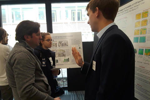 student explaining his poster to a faculty member