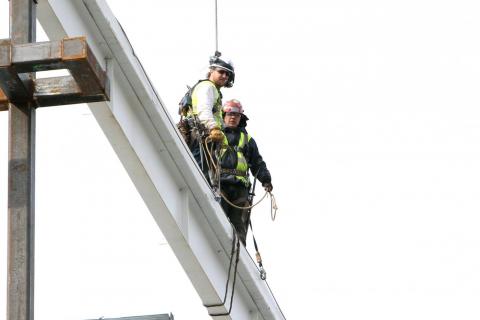 Construction workers releasing the beam from the crane
