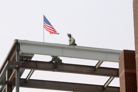 Construction workers with the American Flag on the beam