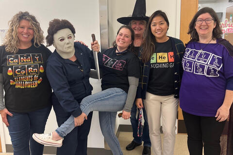 6 people dressed up in periodic table shirts with person dressed up as michael myers from the movie halloween